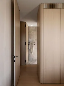Modern minimalist bathroom with wooden doors and floor, featuring a towel rack with a towel hanging on it.