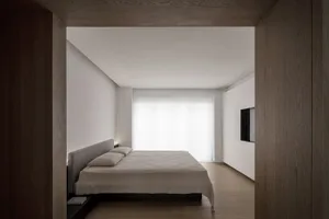 Modern minimalist bedroom with a wood floor and white walls.