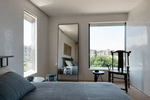 A minimalist bedroom featuring a blue bed and a large mirror.