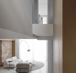 View of a modern minimalist living room with light-colored furniture, a glass table, and a floor lamp.