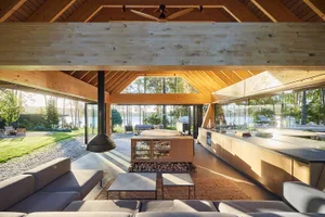 A modern, minimalist residential kitchen featuring wooden elements and a connection to the outdoors.