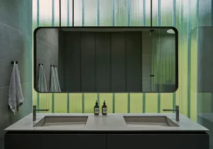 A sleek modern bathroom with concrete countertops, a glass shower enclosure, and minimalist design.