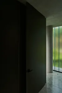 A minimalist modern interior design featuring concrete walls and a large window.