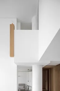 A minimalist modern interior featuring a concrete column and wooden beams.