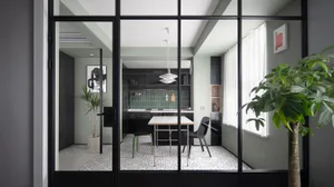 A modern kitchen and dining area with a table and chairs, modern lighting, and mixed materials.