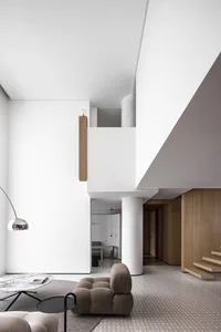 A minimalist living room with wooden elements and white walls, featuring a grey sofa and a marble coffee table.