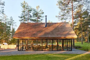 A modern residential retreat with a thatched roof surrounded by trees and greenery.