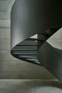 A minimalist metal staircase with concrete walls.