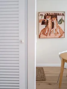 Modern art depicting three gazelles sitting on a wall, with rustic wooden floor and sleek white closet.