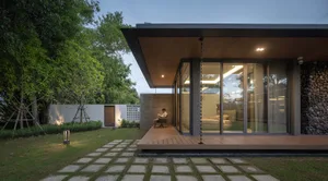A modern minimalist house exterior with wood and concrete materials, featuring a covered patio and a well-maintained garden.