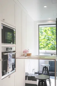 A minimalist kitchen with white cabinets and modern appliances.