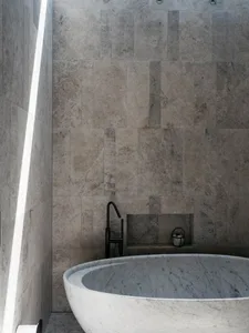 Modern bathroom with marble walls, bathtub, and black faucet.