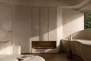 A modern minimalist living room featuring neutral materials and a cozy fireplace.
