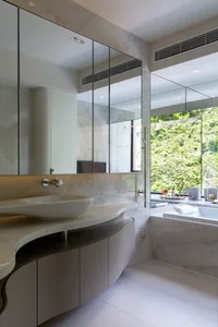 A modern marble bathroom with a floating vanity and large window overlooking greenery.