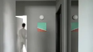 A minimalist entryway featuring abstract wall art with a green and red color scheme.
