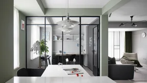 A modern living, dining, and office space featuring glass walls, cement flooring, and contemporary furniture.