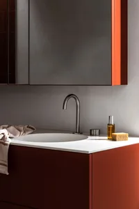 A modern industrial bathroom featuring a sleek, metallic counter with a sink and minimalist design elements.