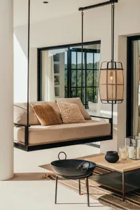A minimalist living room featuring a floating sofa, hanging lantern light, and a wooden coffee table.