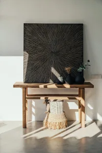 A modern console table crafted from wood with a minimalist design, featuring black vases and decorative items on top.