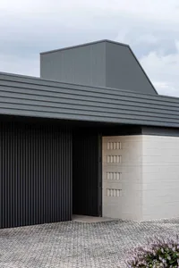 A modern entryway with a metal-cladding on top and a stone base.