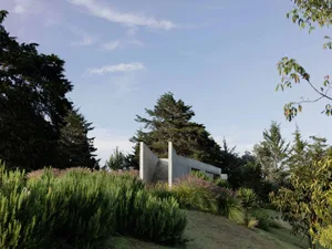 A modern landscape featuring concrete structures surrounded by greenery and trees.