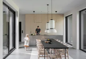 Modern minimalist residential kitchen dining area with wood, black, white, and concrete finishes and a long dining table.