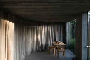 A minimalist living room featuring fabric curtains and concrete elements.