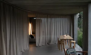 A minimalist living space featuring textured curtains and a warm, soft lighting setup.