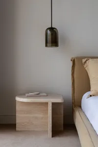 A modern bedside table with a brown bed frame and a hanging light fixture.