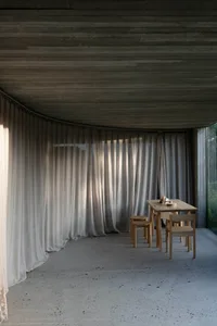 A sleek, modern dining room with a wooden table and chairs, featuring textured linen curtains and a wooden ceiling with horiz