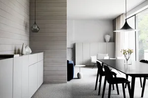 Contemporary dining area featuring a mix of materials like wood, metal, and glass, with minimalist furniture and large window