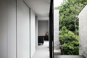 Interior design showcasing modern concrete walls and floor with a large window providing a view of greenery and natural light