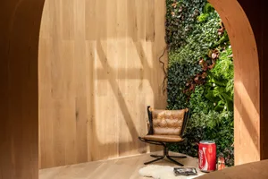 A modern interior living room with wooden walls, a green plant wall, a brown leather chair, and a Coca-Cola can.