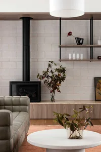 Modern living room featuring a concrete brick wall with a black fireplace, floating shelves, and a grey sofa.