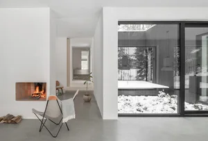 Minimalist living room with concrete floor, glass windows, and fireplace.
