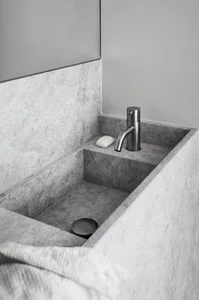 A minimalist bathroom with a concrete sink and a stainless steel faucet.