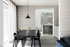Modern dining room featuring a black pendant light, a long wooden dining table, and modern black chairs.