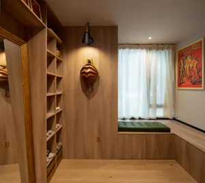 A modern closet with wooden shelves and a window seat with green cushions.