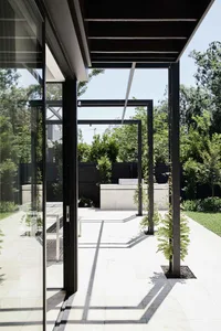 Modern concrete veranda with black metal columns and large glass sliding doors.