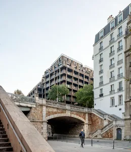 一張現代都市橋樑與住宅建築的照片，建物由混凝土、玻璃與石材構成。