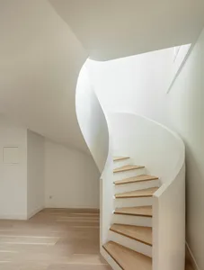 A modern, white, curved staircase made of wood and concrete in an interior design setting.