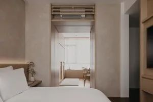 A minimalist bedroom with a white bed, wooden knobs, and a white floor.