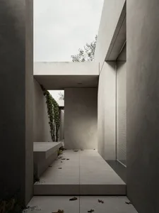 A minimalist interior space featuring concrete walls and floor, with a skylight providing natural light.