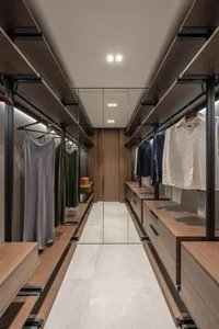 A modern closet with wood shelves, hanging clothes, and a mirrored door.