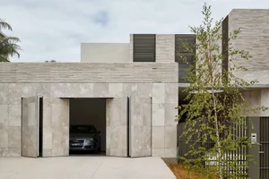 Modern architectural house with a concrete entry gate and a car parked inside.