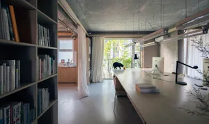 Modern, industrial-style workspace with concrete finishes and a long desk.