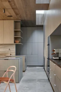 Modern kitchen interior featuring wooden cabinets and concrete flooring.