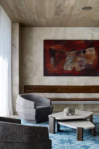Modern living room featuring a large colorful abstract artwork hanging above a leather-clad lounge area, adorned with a white
