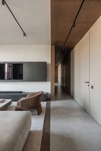 A modern living room featuring minimalist design with concrete floor and furniture, and dark ceiling beams