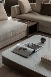 Modern living room with beige sofas, marble coffee table, and books.